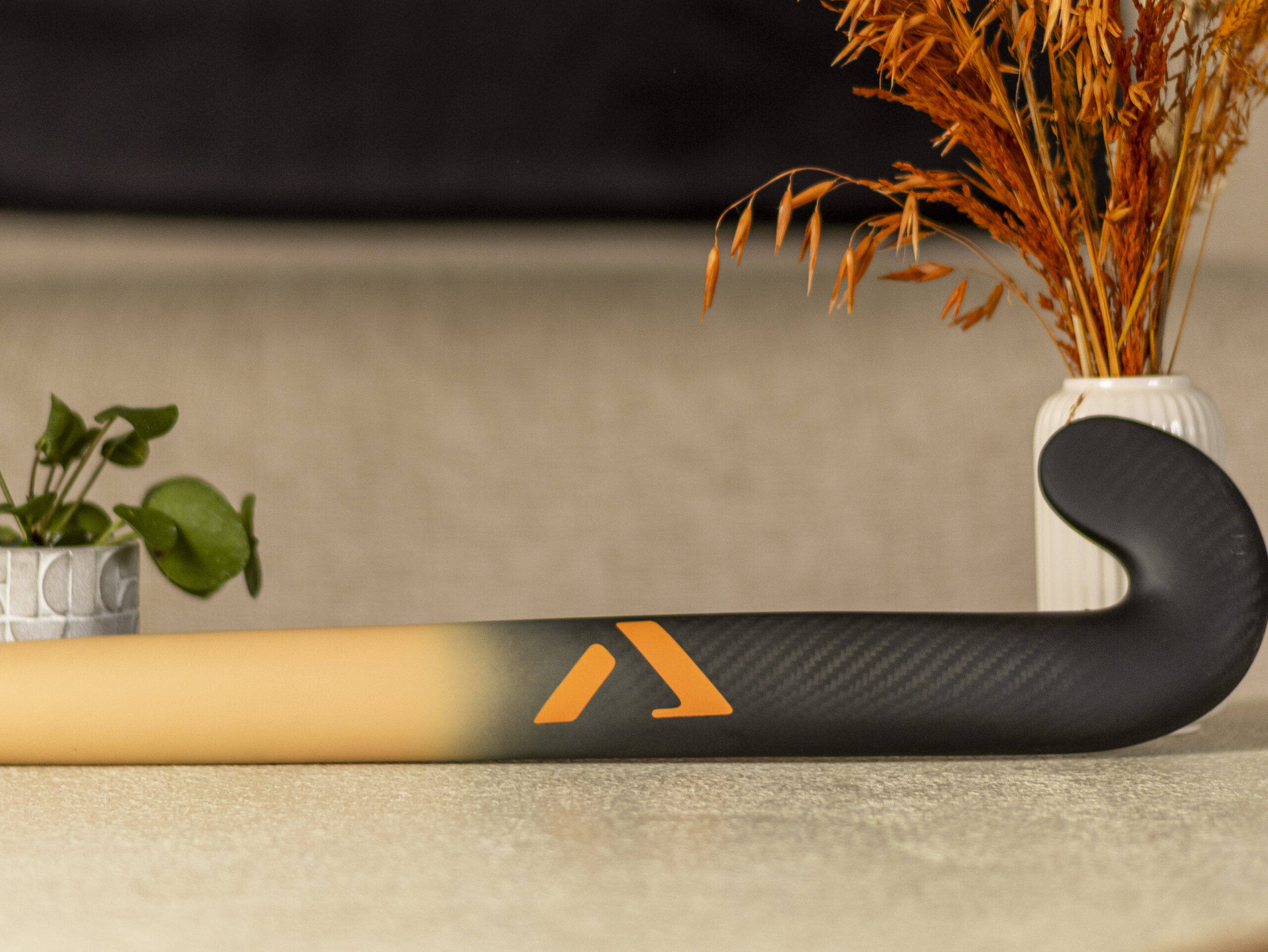 A-LIFE Ibiza Drop premium low bow hockey stick on beige textured background, minimalist design.